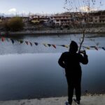 women standing in front of nako lake in evening watching sunset