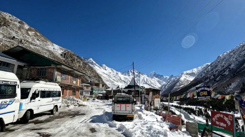 snow covered chitkul village and vehicles parked in sangla