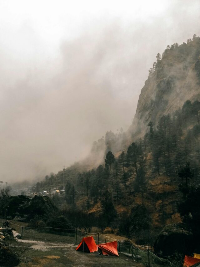 Misty mountainside with red tents at a campsite in Kasol, India, creating a serene outdoor scene.