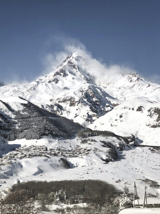 Breathtaking snowy mountain landscape under a clear blue sky, ideal for winter and travel themes.