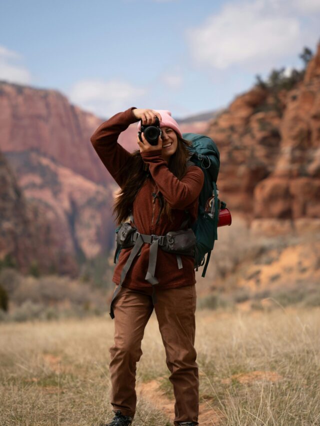 A woman hiker with a backpack captures the majestic Utah landscape with her camera.