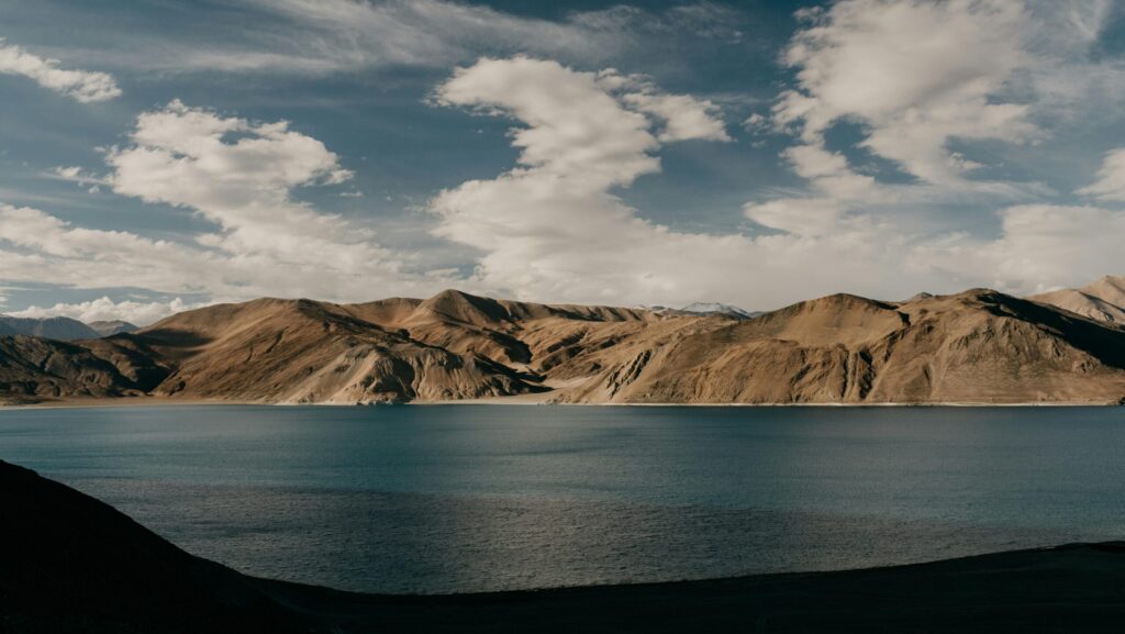 Azure sea cloudy sky flowing near range of rocky cliffs against cloudy sky in nature on summer day at seaside