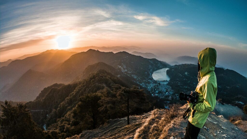 A lone adventurer photographs the breathtaking sunrise over Nainital's mountains.