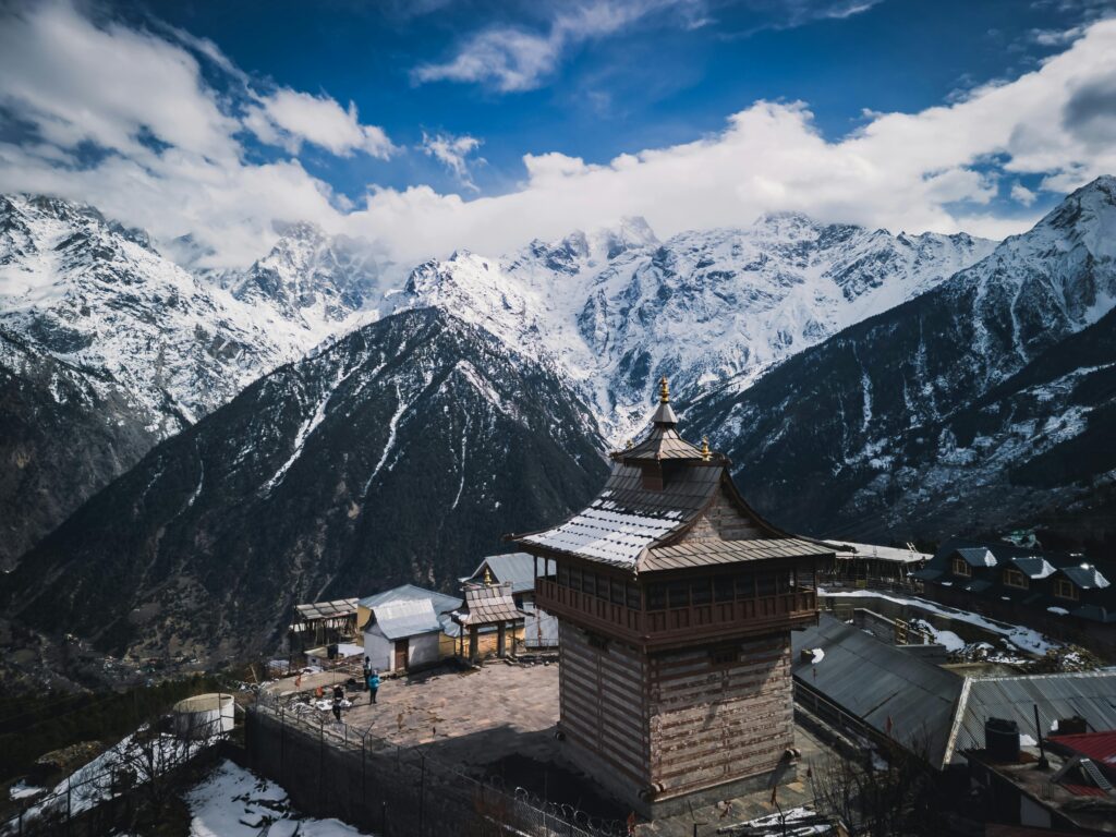 pexels-photo-32261679-32261679 Stunning view of Kinnaur Kailash temple and snow-covered Himalayan mountains under a vibrant sky.