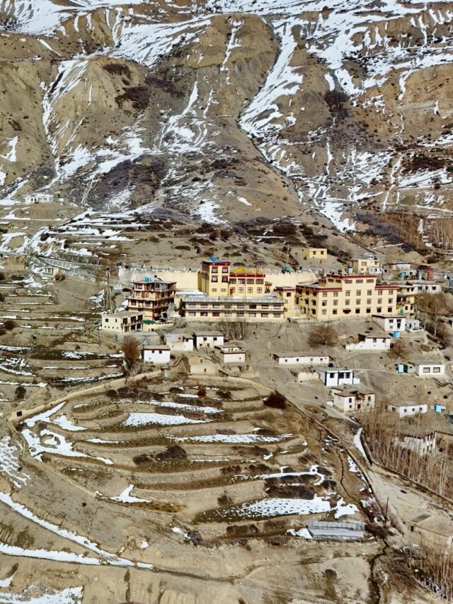 Aerial view of a scenic village in Spiti Valley, Himachal Pradesh, India, showcasing terraced landscapes and traditional architecture.